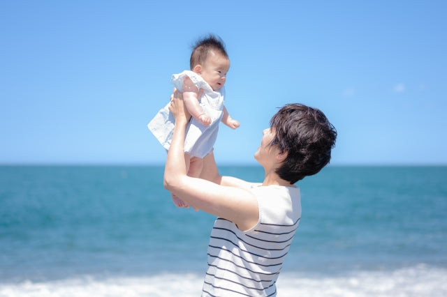 海辺で赤ちゃんを抱く女性