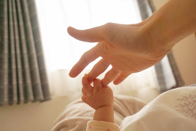 お母さんの指を握る赤ちゃんの手